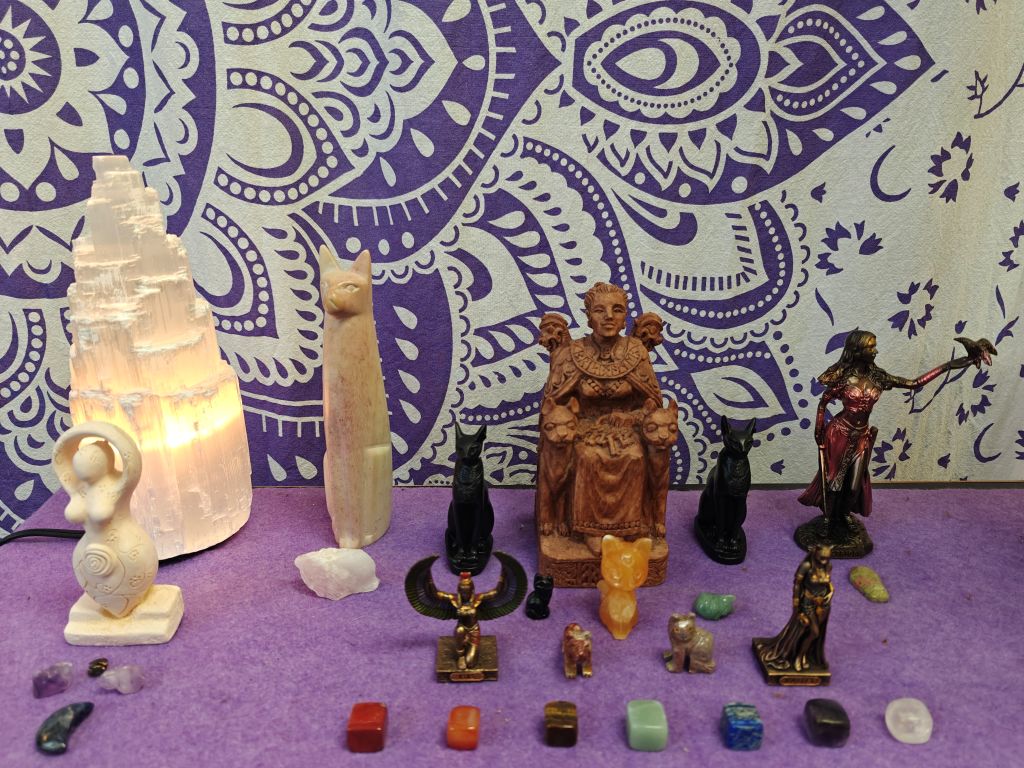 altar with crystals goddess statues and selenite tower lamp